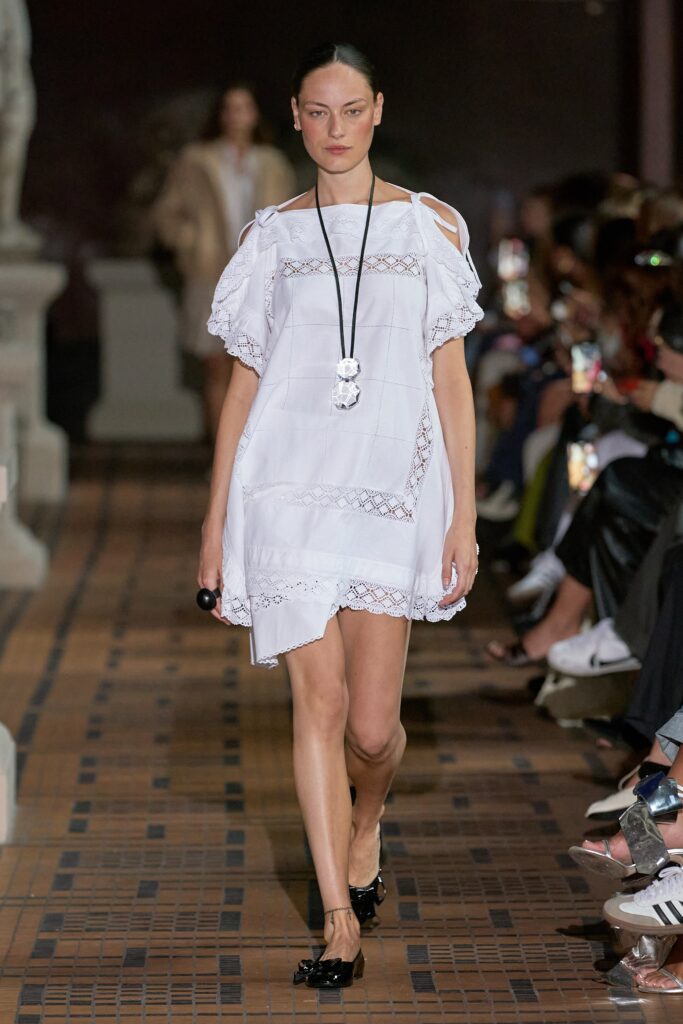 A relaxed white off-shoulder dress with an asymmetric hem and embroidered details.