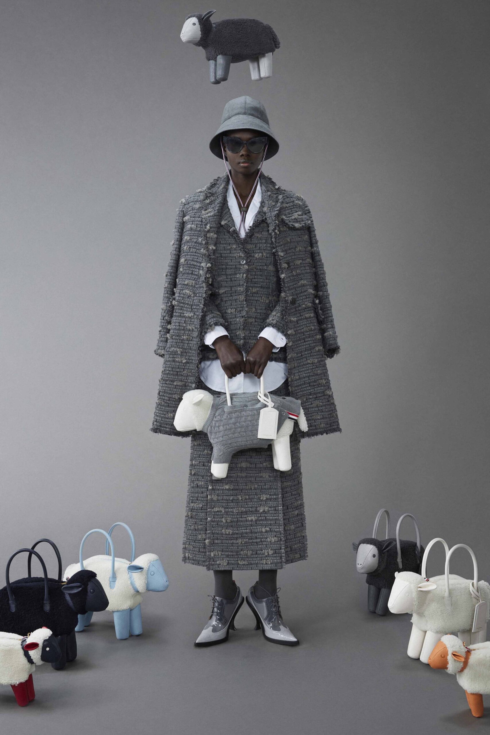 A fitted gray tweed coat with a collared long-sleeve design, paired with an asymmetric skirt.