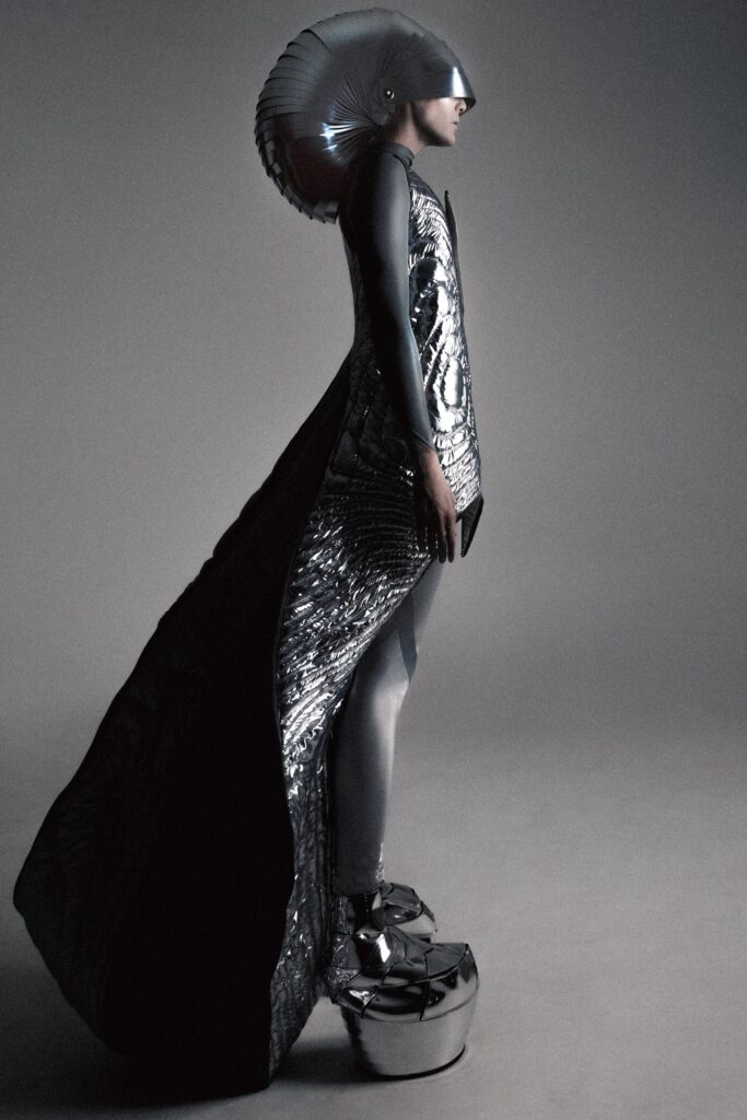 A fitted black silk dress with a high neckline and asymmetric design.