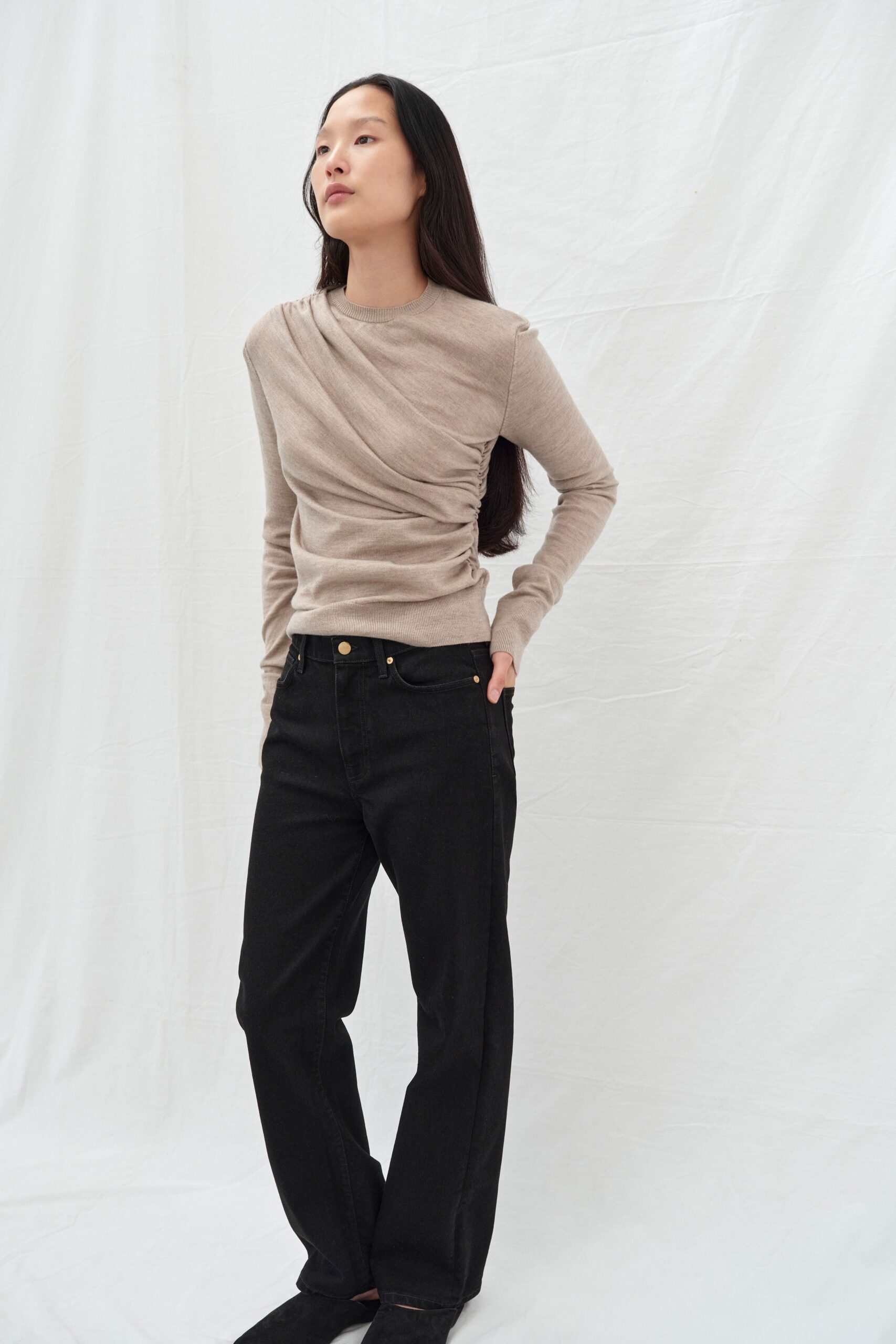 A relaxed beige long-sleeve draped top paired with wide-leg black pants.