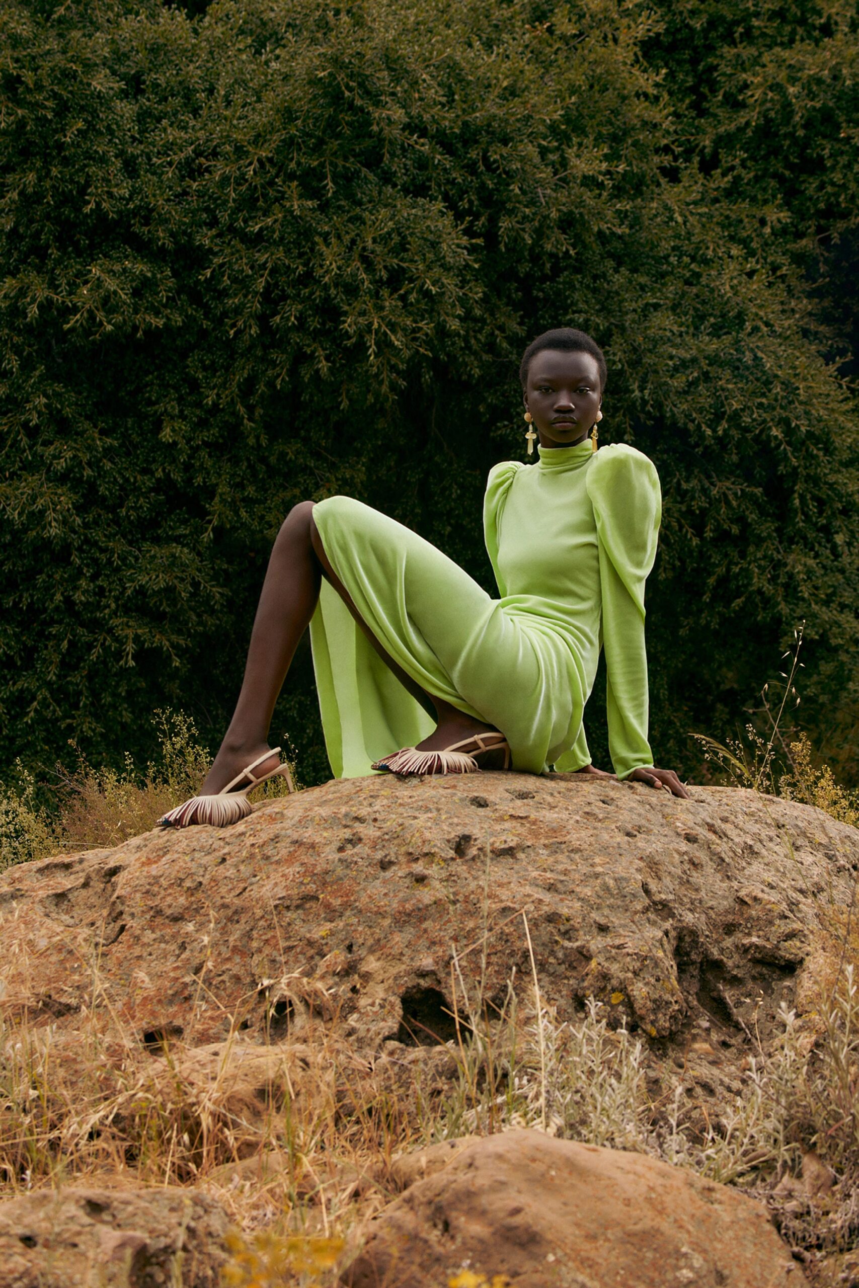 A fitted green long-sleeve dress with a high neckline and a stylish slit detail.