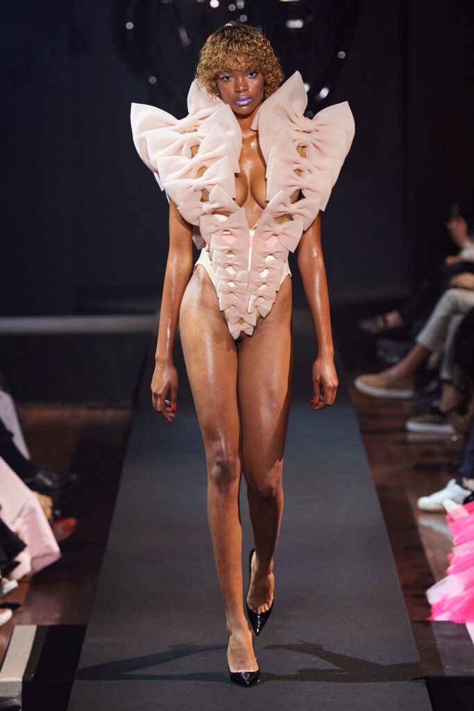 A fitted pink silk dress with a V-neckline and ruffled design details.