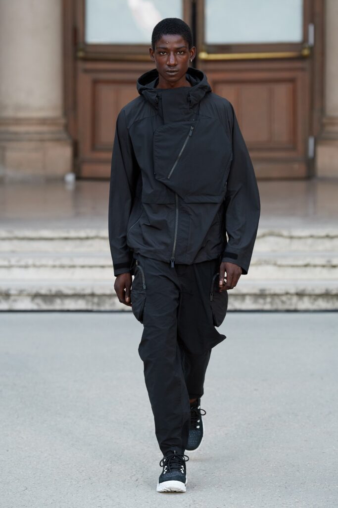 A relaxed black jacket with a hood and zippered details paired with matching pants.