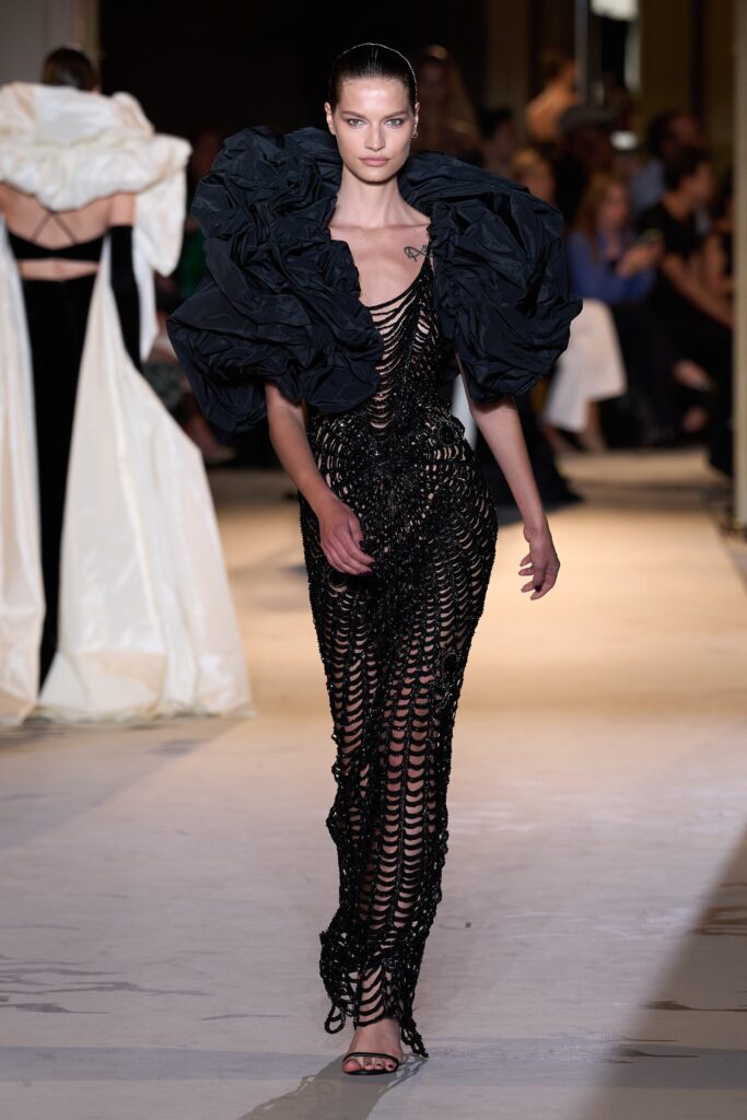 A fitted black silk dress with a V-neckline and asymmetric design details.