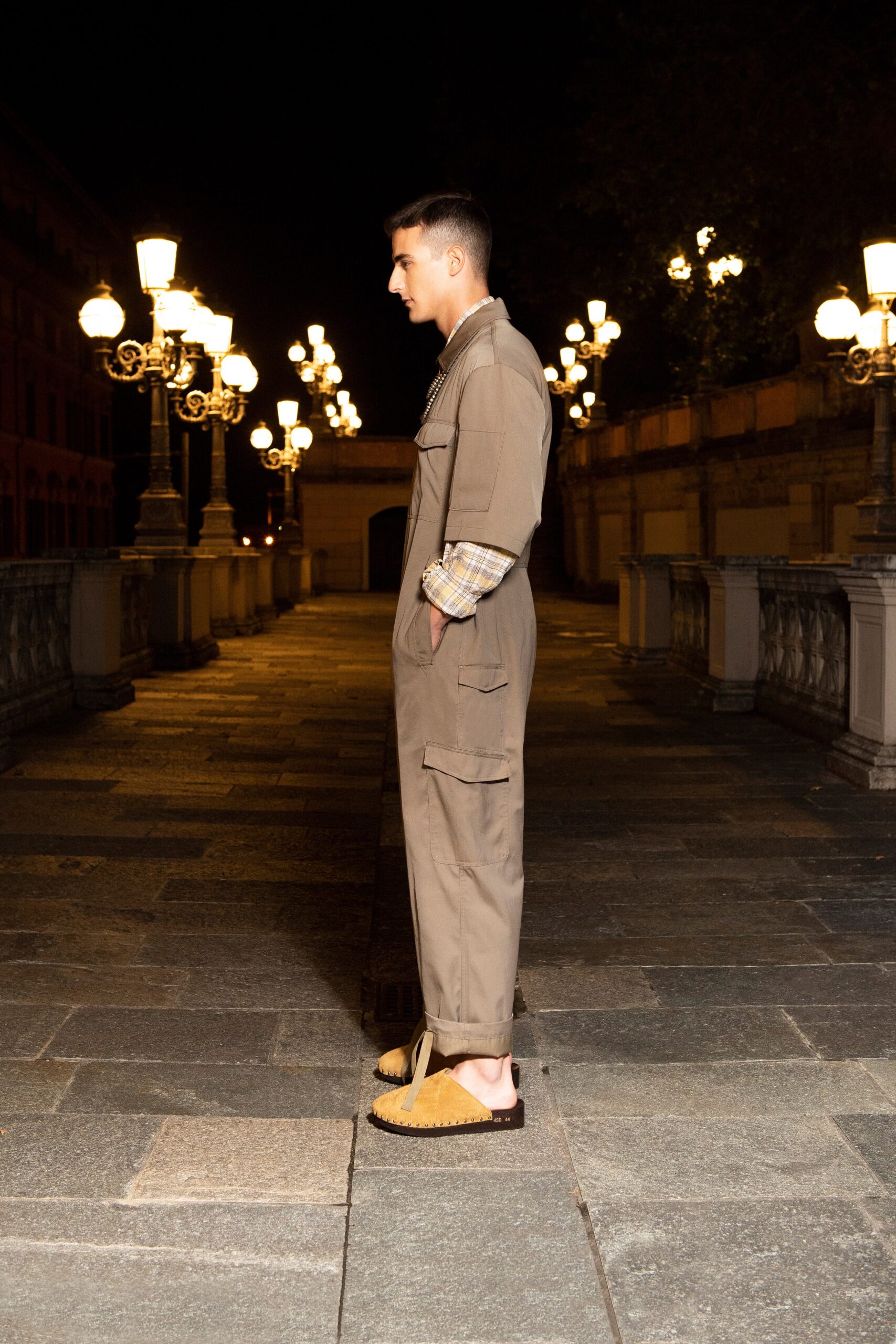 A relaxed beige cotton jumpsuit with long sleeves and a collared neckline, featuring button details.