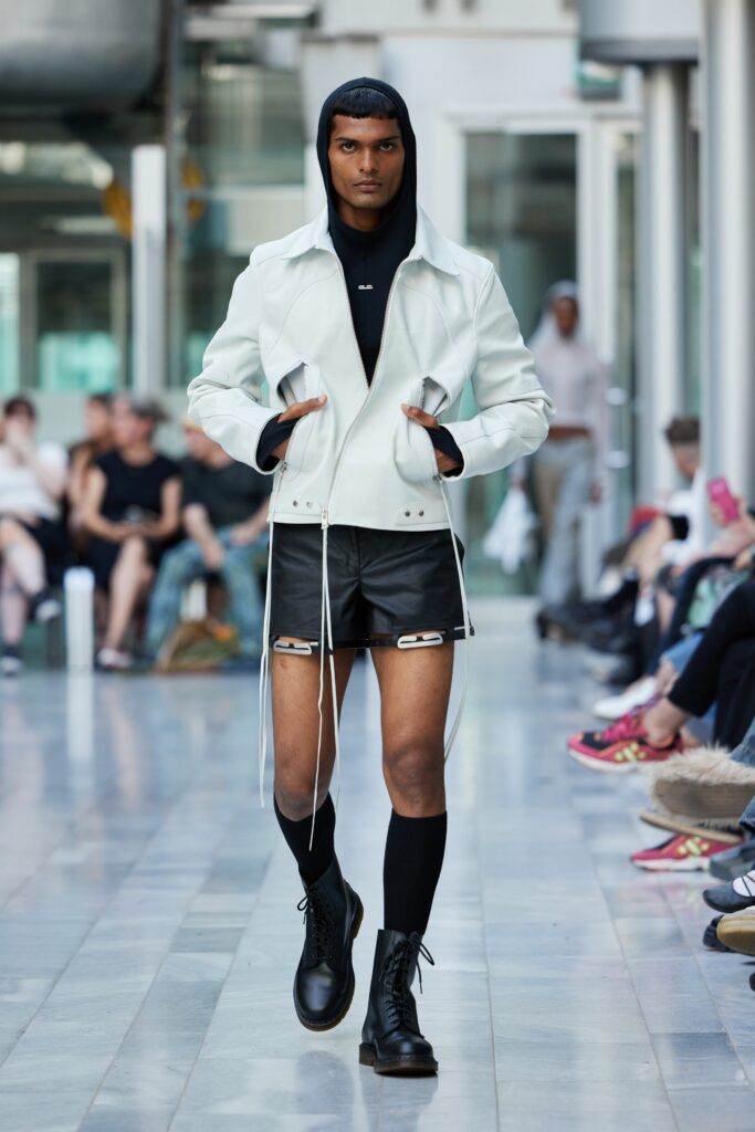 A fitted white leather jacket paired with black shorts, creating a modern and edgy look.