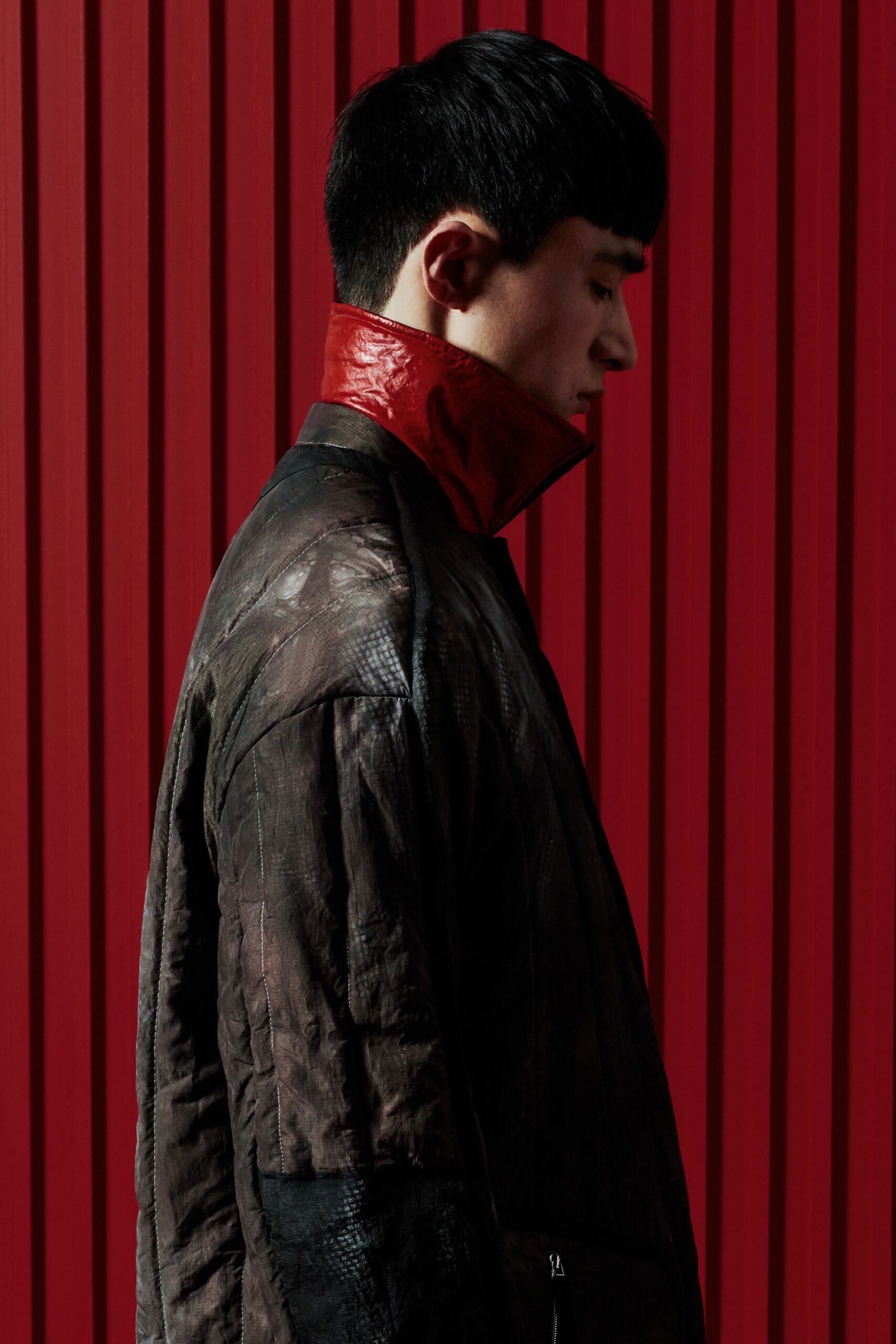 A relaxed black leather coat featuring a long sleeve and a striking red collar.