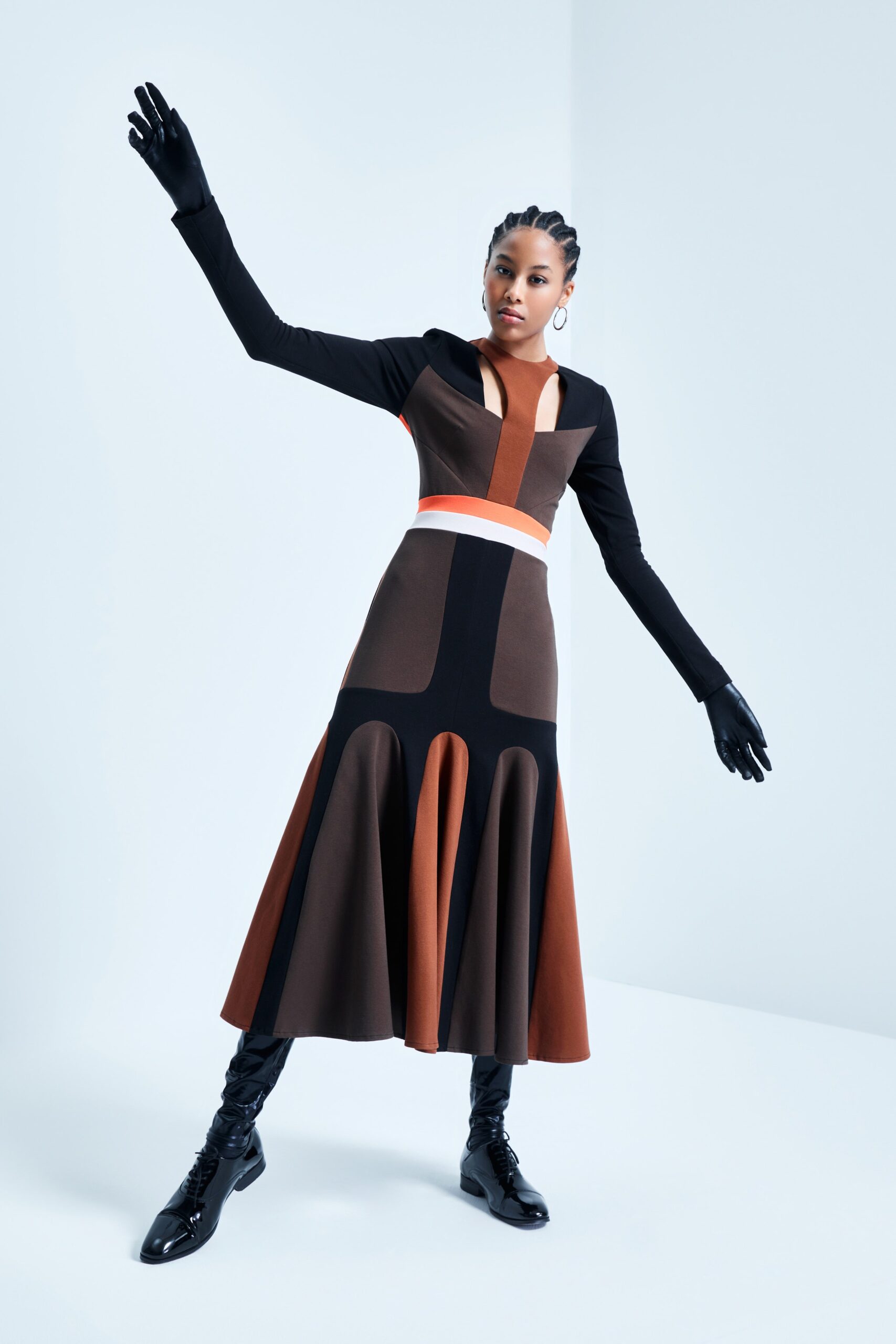 This fitted dress showcases a striking color-blocked design, blending rich browns and blacks with a crisp white accent. The flared hem adds a dynamic movement, while the long sleeves and V-neckline create a sophisticated silhouette that commands attention.