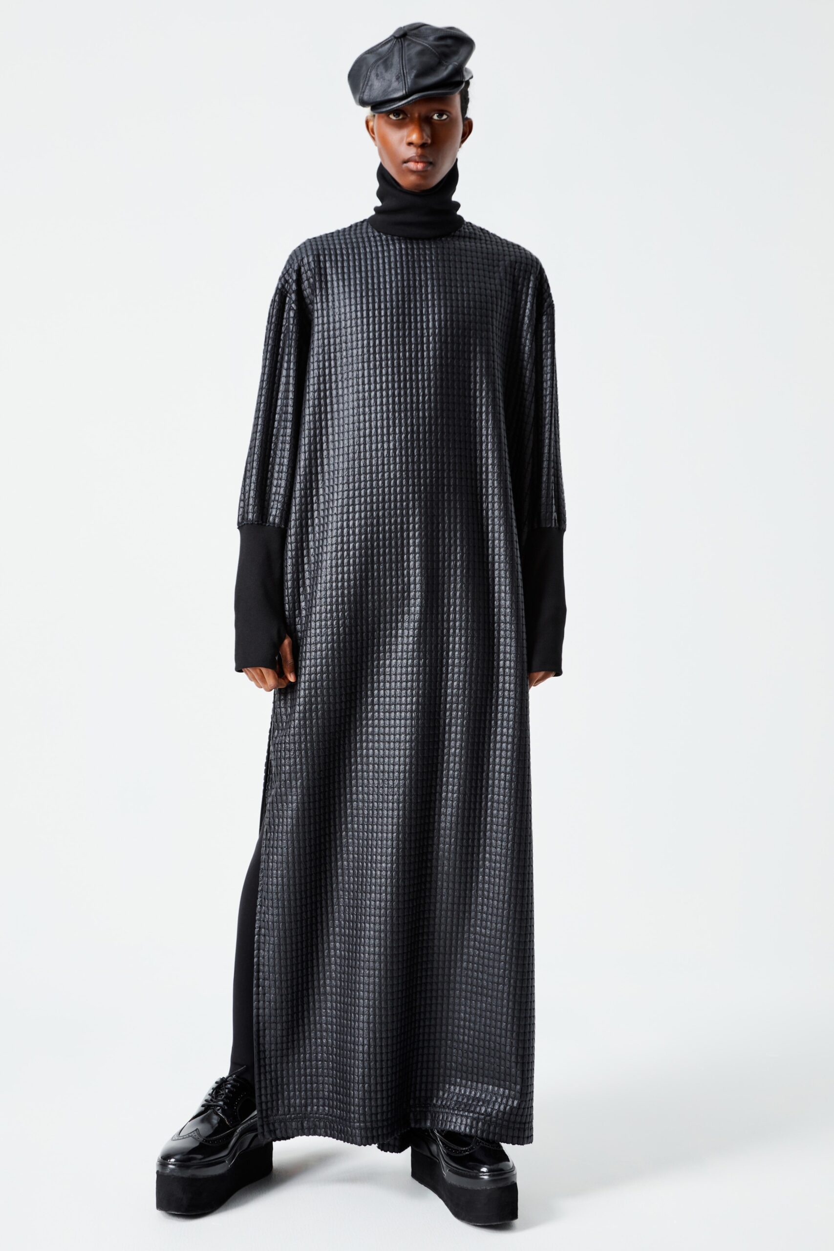 This relaxed dress features a high-neck design that flows effortlessly to an asymmetric hemline. The interplay of textures adds depth, while the long sleeves create a striking contrast against the minimalist silhouette.