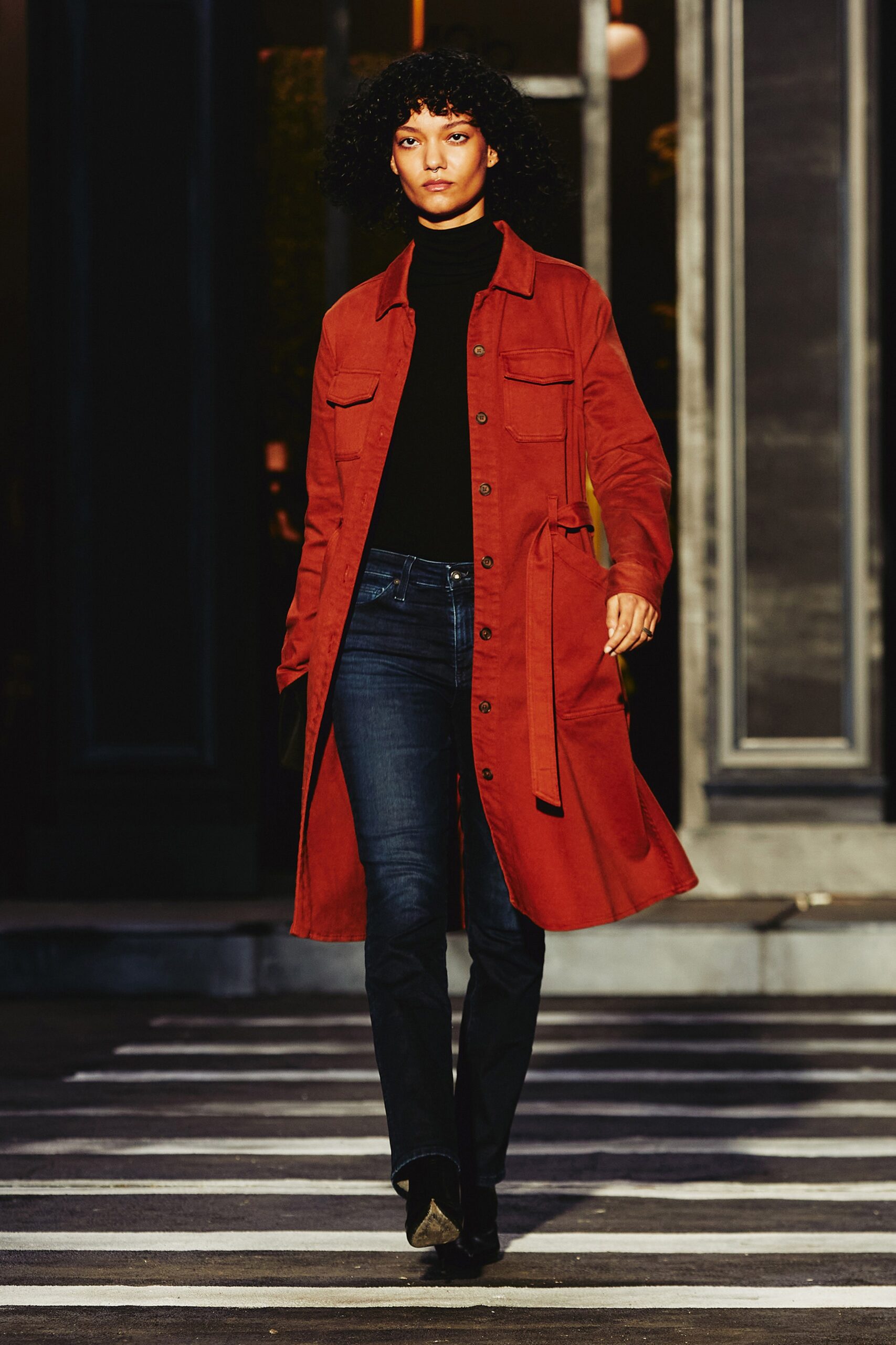 A relaxed red cotton coat with a collared neckline, paired with blue pants.