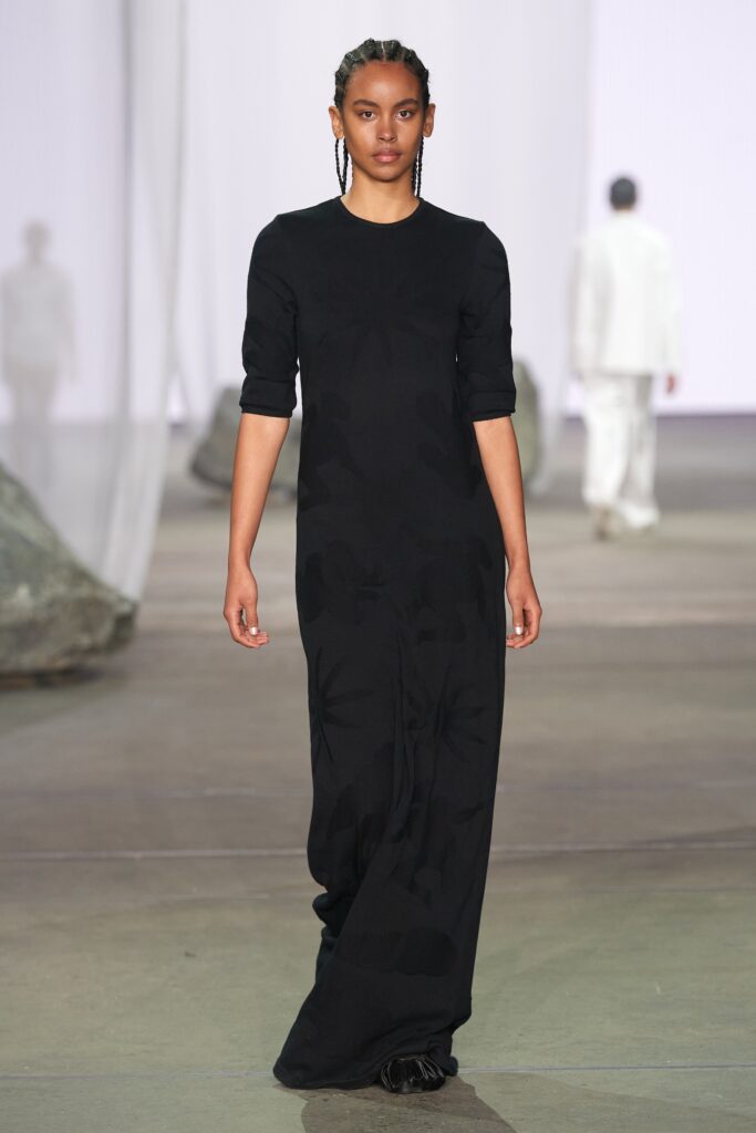 A fitted black cotton dress with long sleeves and a straight silhouette.
