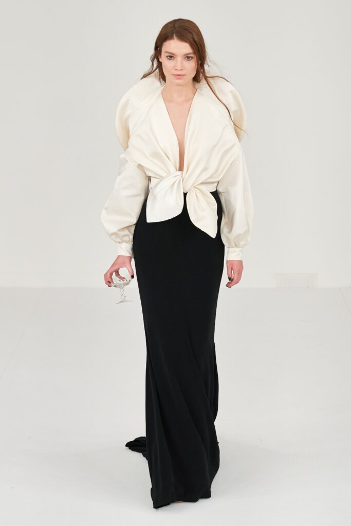 A fitted black dress paired with a white long-sleeve blouse featuring a V-neck and asymmetric design.