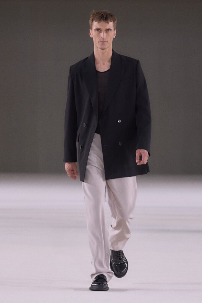 A relaxed black blazer paired with white straight-leg pants, featuring a collared design.