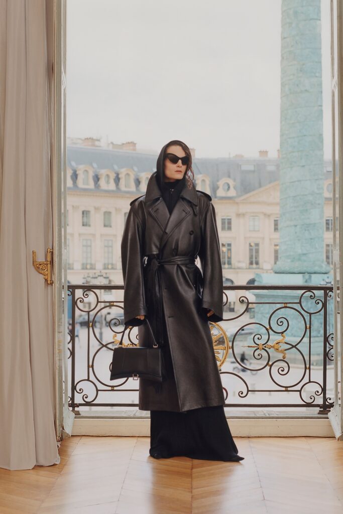 A fitted black leather coat layered over a dress with a V-neckline.