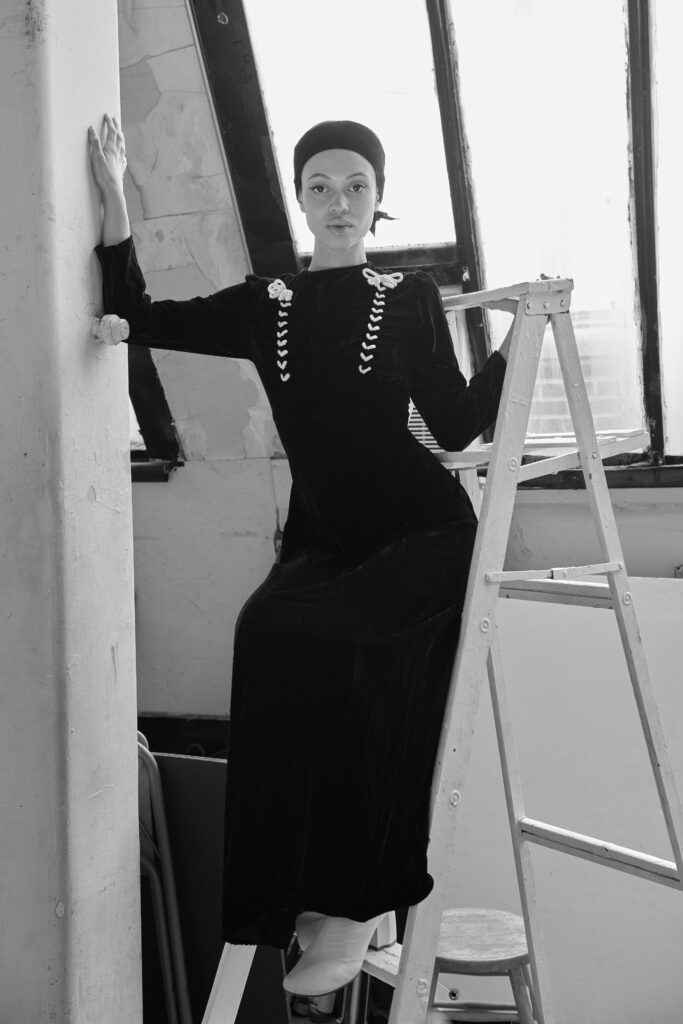 A fitted black velvet dress with long sleeves and a high neckline.