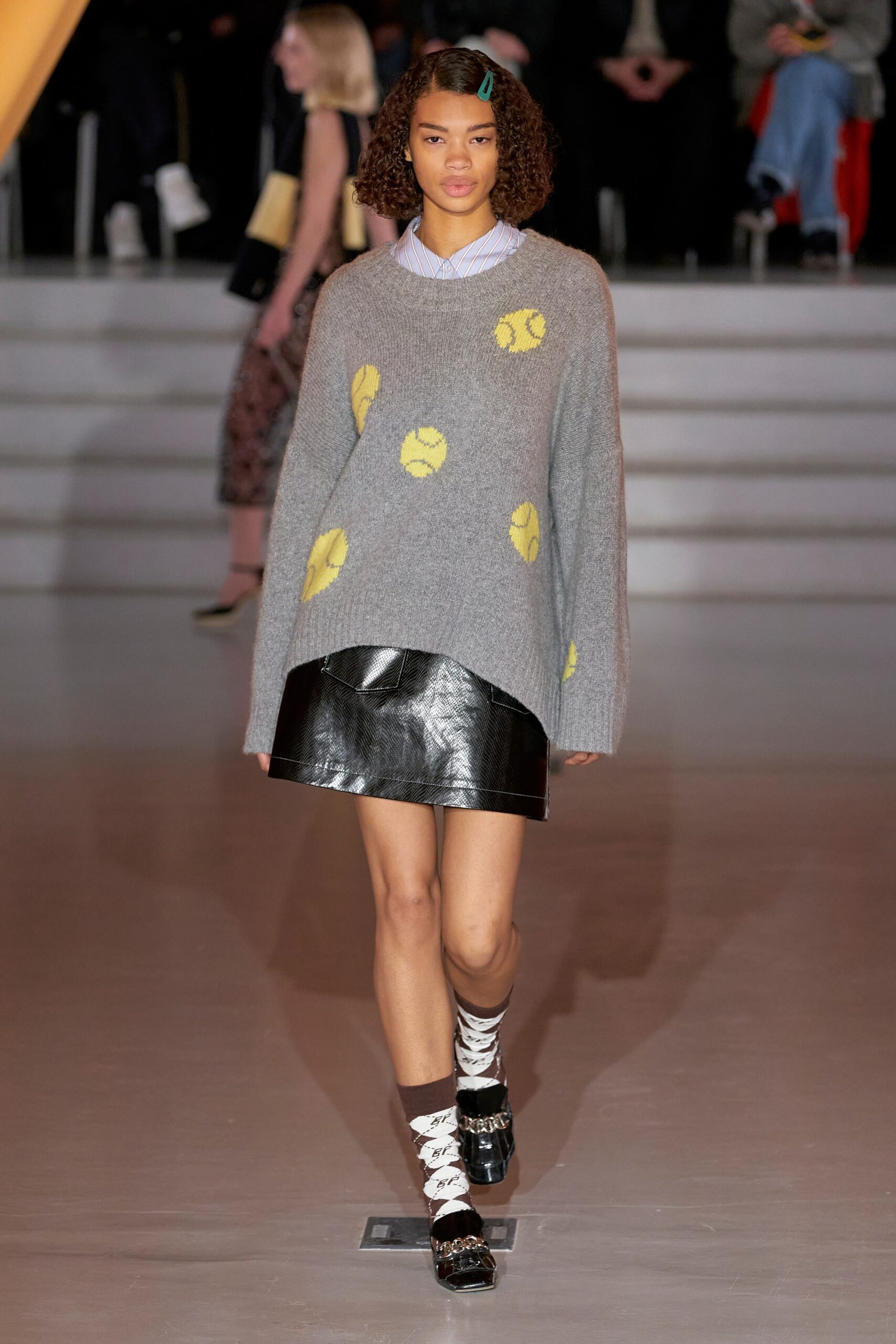A relaxed gray sweater with a collared neckline paired with a black mini skirt.