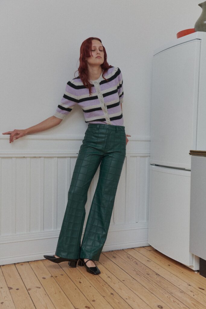 A fitted short-sleeve striped cotton top paired with fitted green leather wide-leg pants.