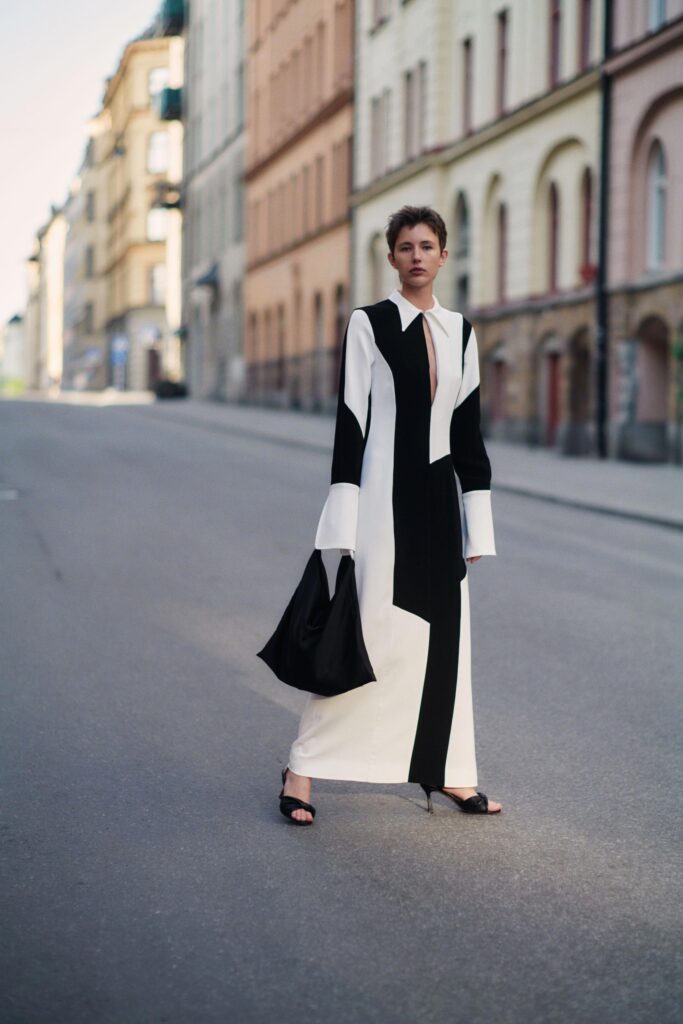 A fitted black and white color-blocked dress with long sleeves and a collared neckline.