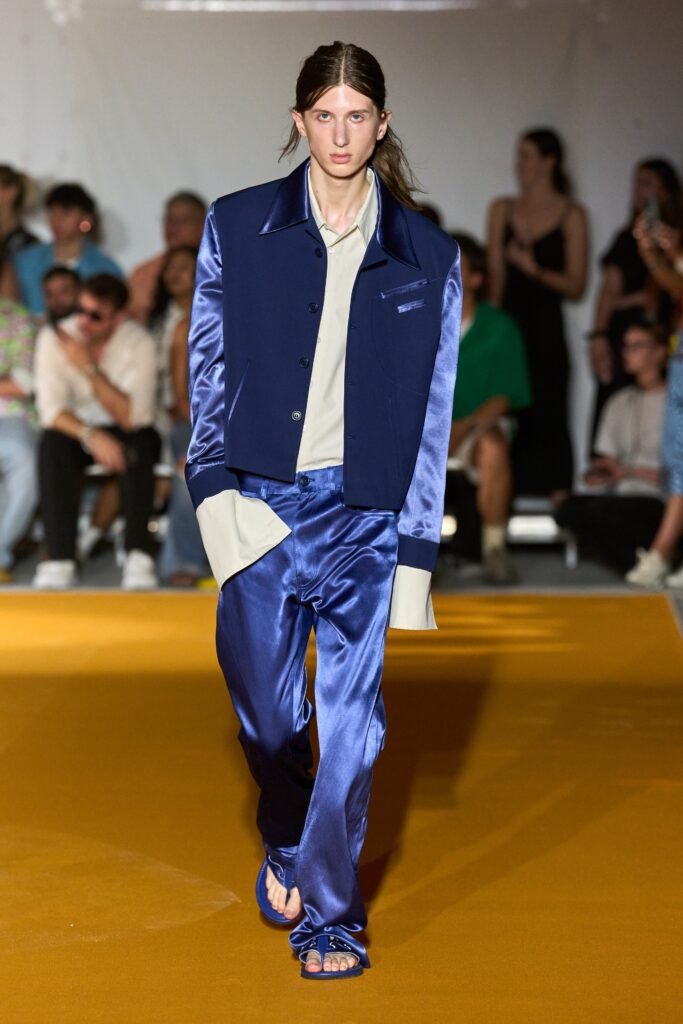 A relaxed blue silk jacket with long sleeves and collared design paired with straight-leg pants.