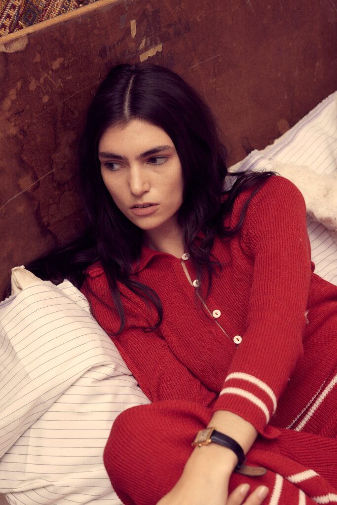 A fitted red cotton sweater with long sleeves and a collared design featuring stripes.