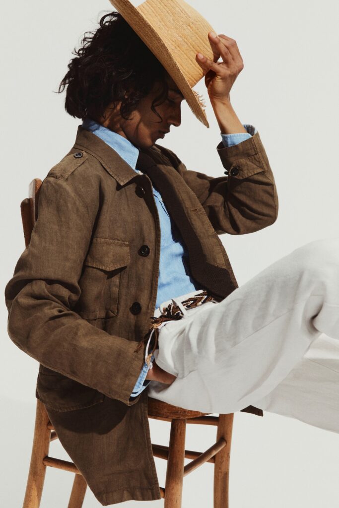 A relaxed brown cotton jacket with long sleeves and a collared design paired with white pants.