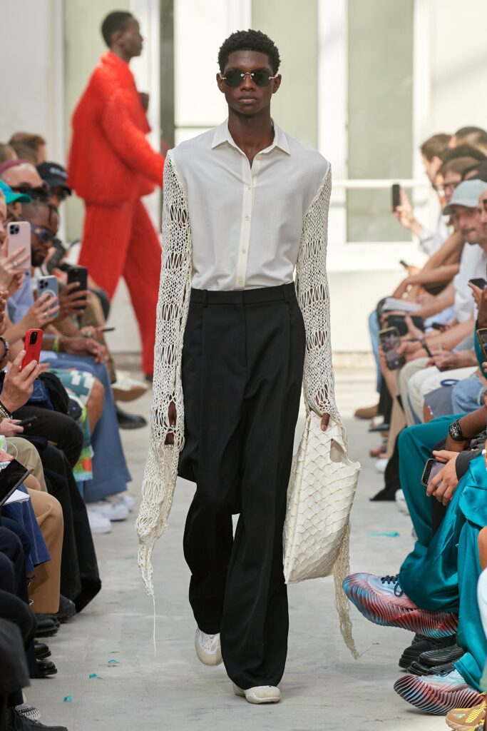 A relaxed white long-sleeve collared shirt paired with black pants, featuring a layered design.