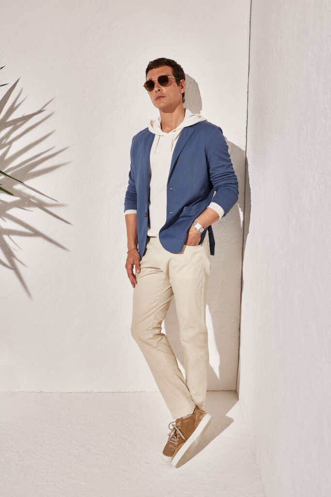 A fitted blue cotton jacket with long sleeves paired with beige pants.