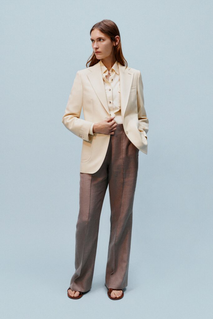 A tailored beige blazer paired with gray straight-leg pants and a collared shirt.