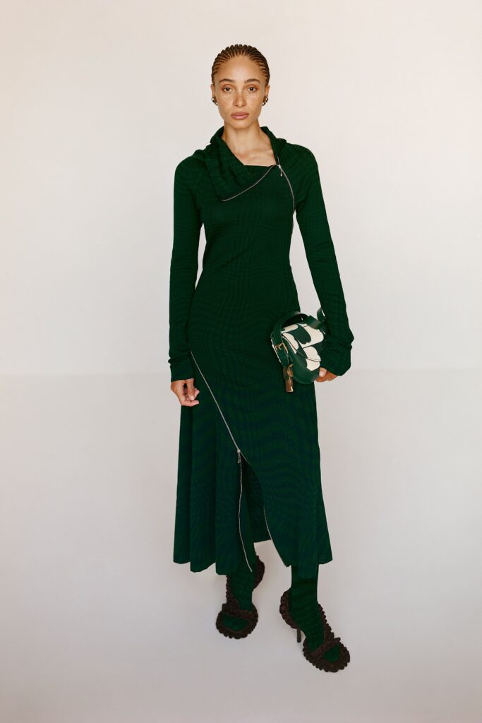 A fitted green long-sleeve dress with a high neckline and asymmetric design.