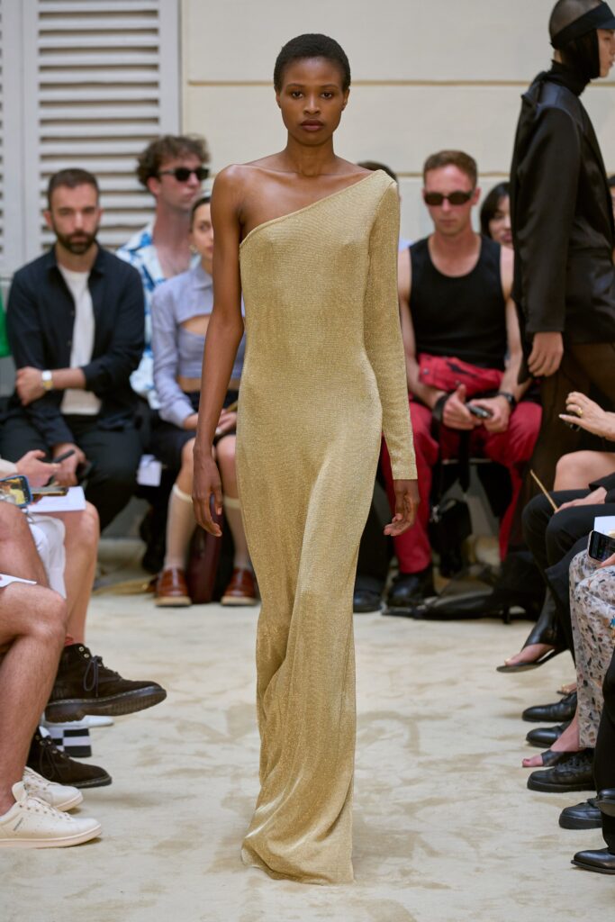 A fitted gold silk dress with an off-shoulder design and straight-leg silhouette.
