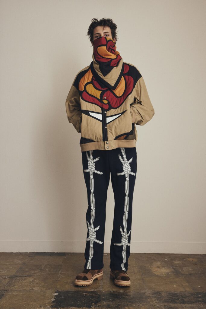 A relaxed beige jacket with a printed design, paired with black pants.