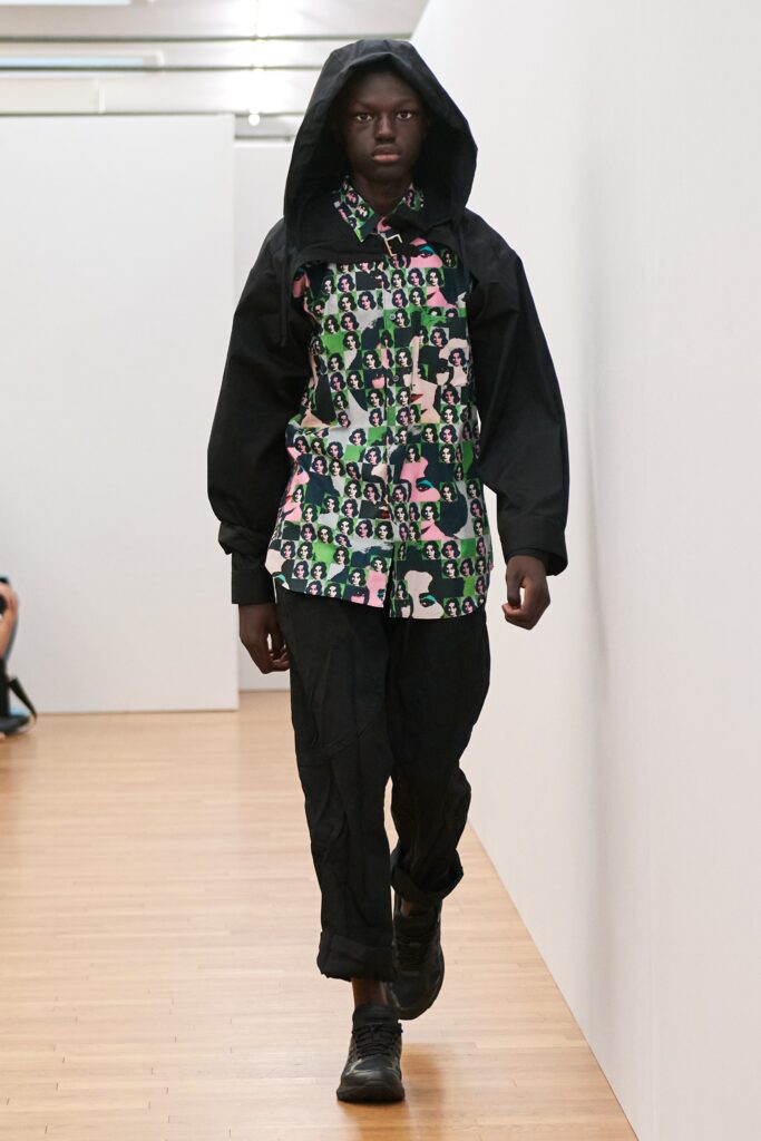 A relaxed-fit multicolor printed shirt with long sleeves and hood, paired with black pants.