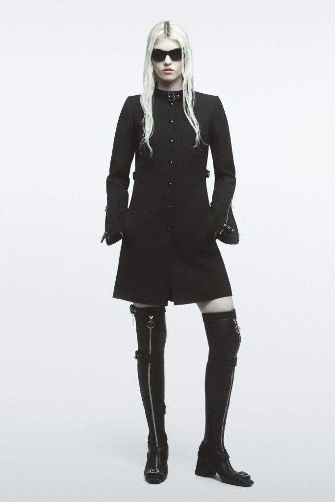 A fitted black wool coat with long sleeves and a collared design, featuring button details.
