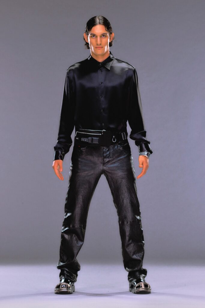 A fitted black silk long-sleeve shirt paired with straight-leg black denim pants.