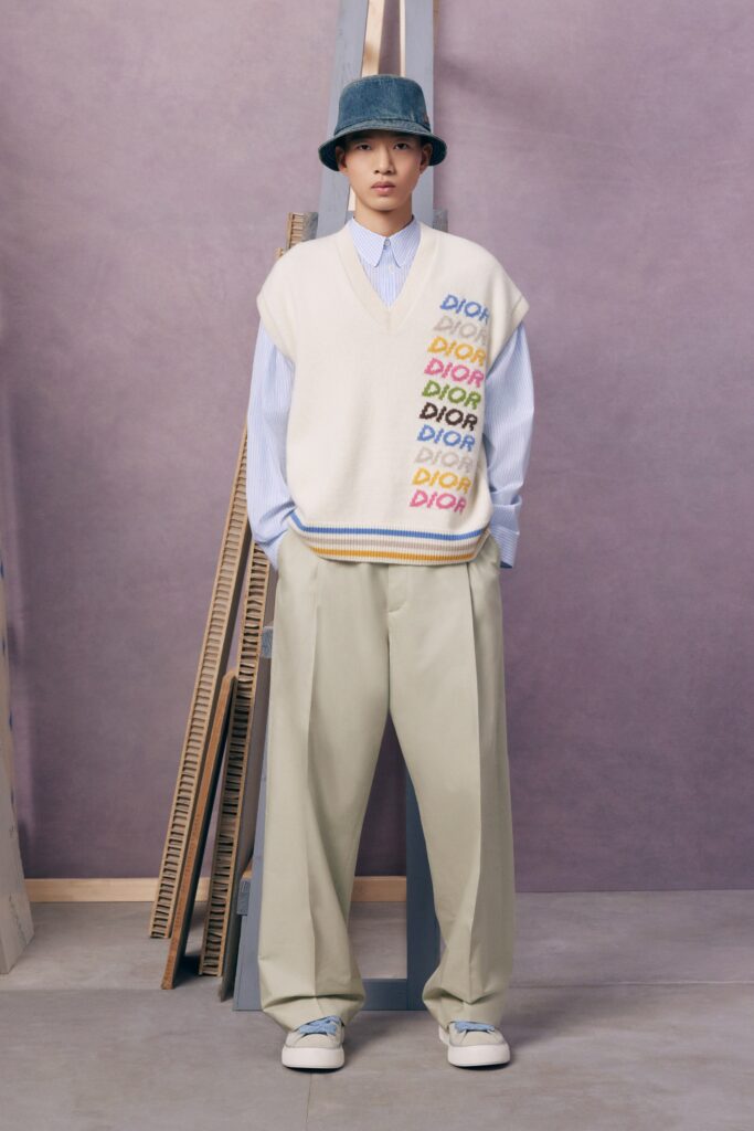 An oversized beige sweater layered over a blue shirt, paired with loose-fitting beige pants.