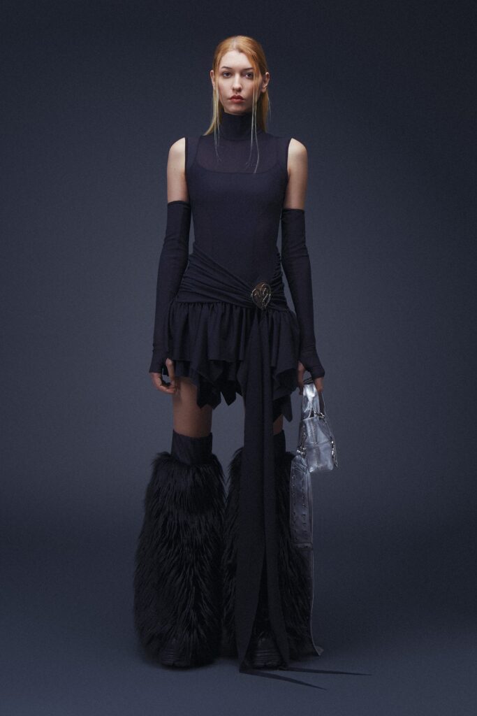 A fitted black silk sleeveless dress with a high neckline and asymmetric, tiered design.