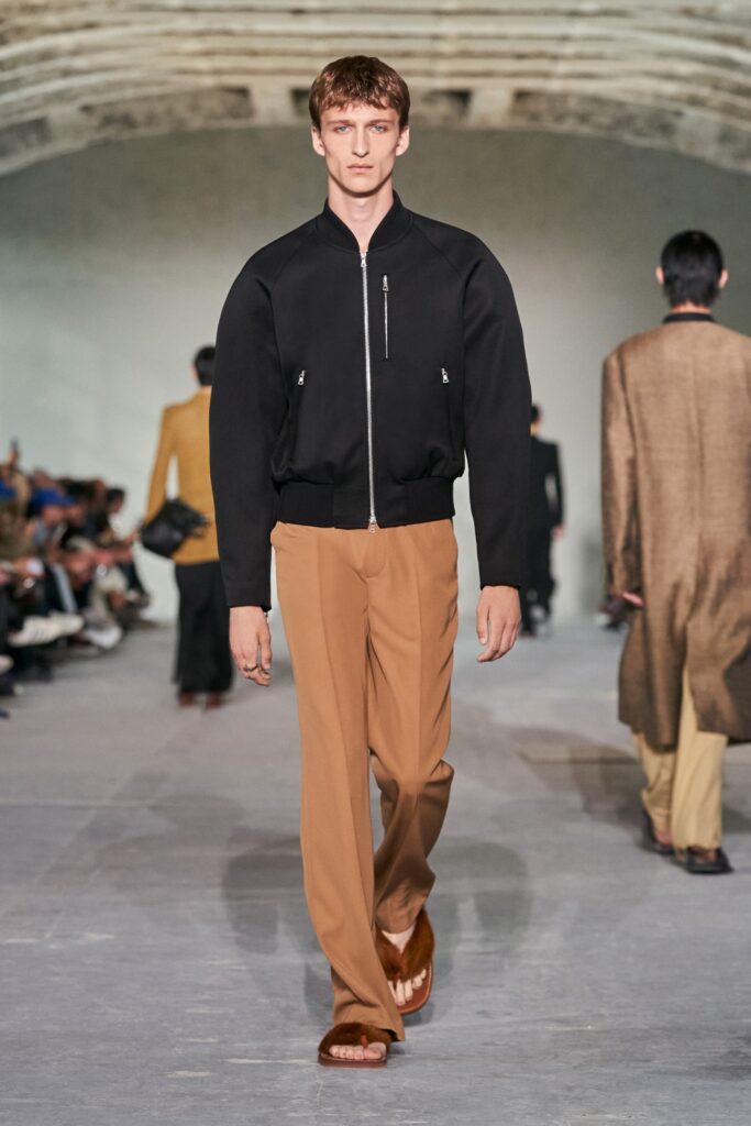 A relaxed black jacket paired with straight-leg brown pants for a modern look.