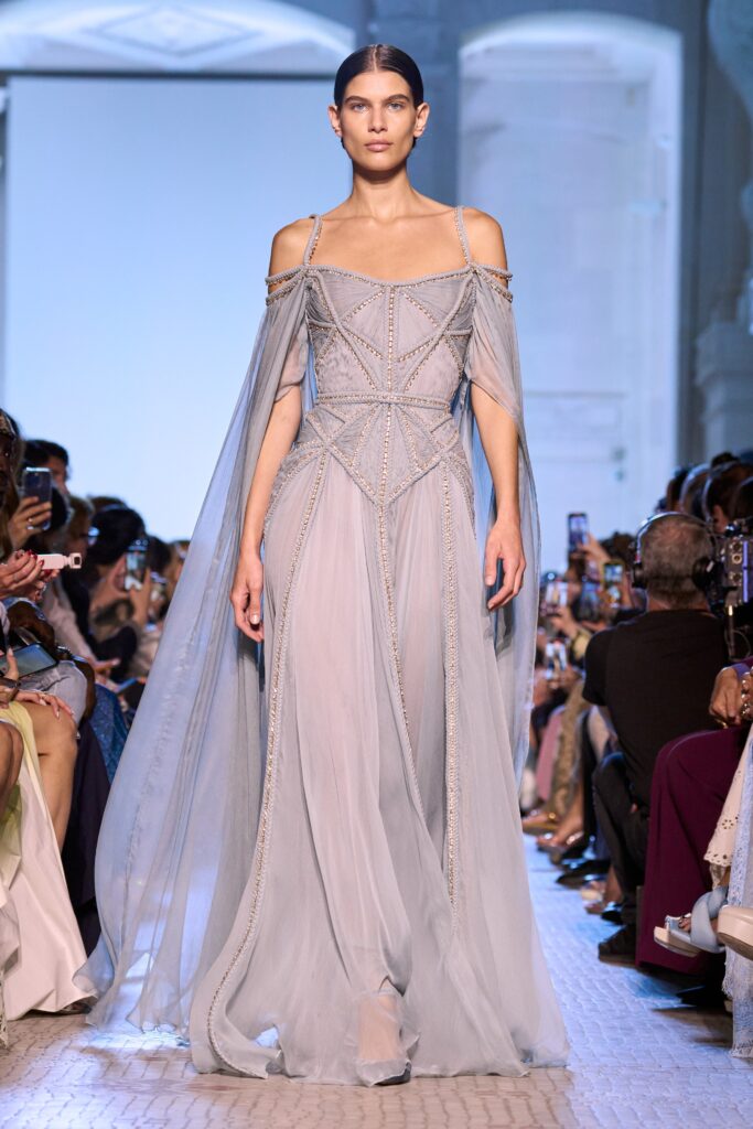 A fitted blue silk off-shoulder gown with intricate embroidery and a flowing silhouette.