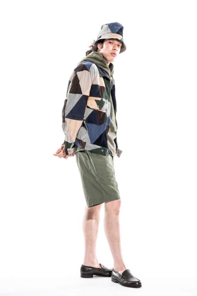 A relaxed multicolor jacket with long sleeves and printed design, paired with green shorts.