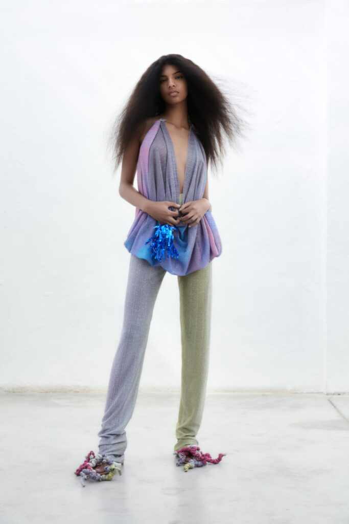 A fitted sleeveless top with a V-neck and asymmetric design paired with fitted pants in green.