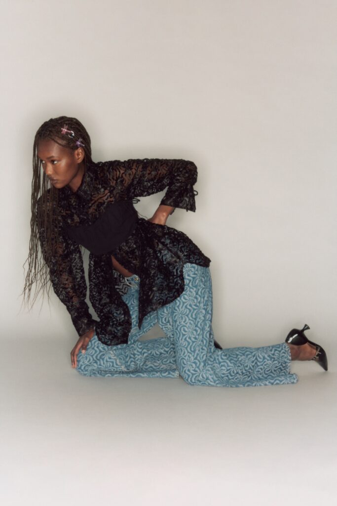 A fitted black lace long-sleeve blouse paired with printed blue pants.