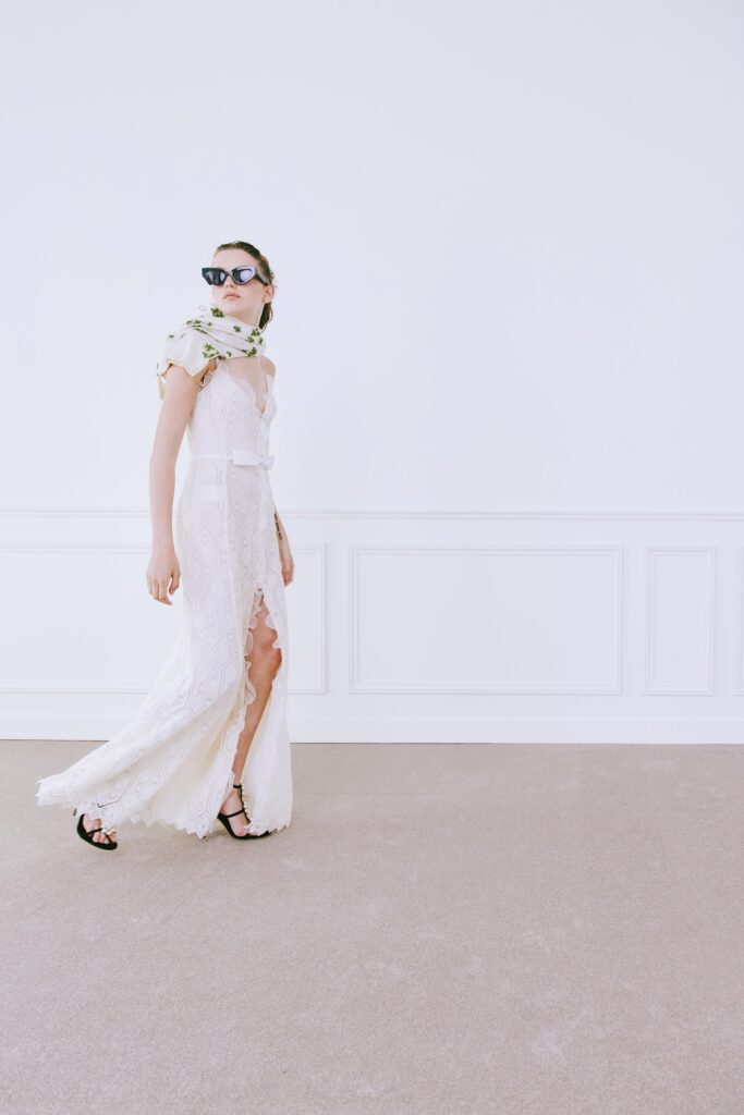 A fitted white lace dress with a V-neckline and a stylish slit.