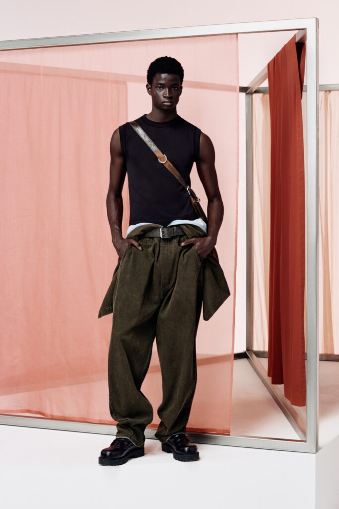 A relaxed black sleeveless top paired with high-waisted wide-leg green pants.