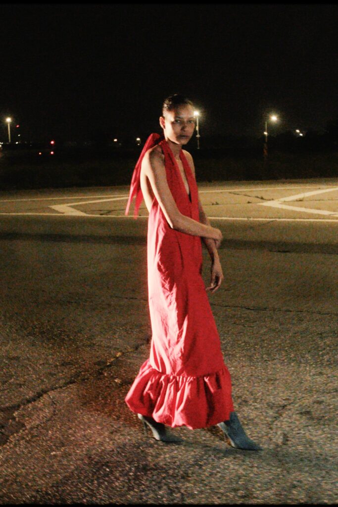 A fitted red cotton dress with a sleeveless design and tiered hem.
