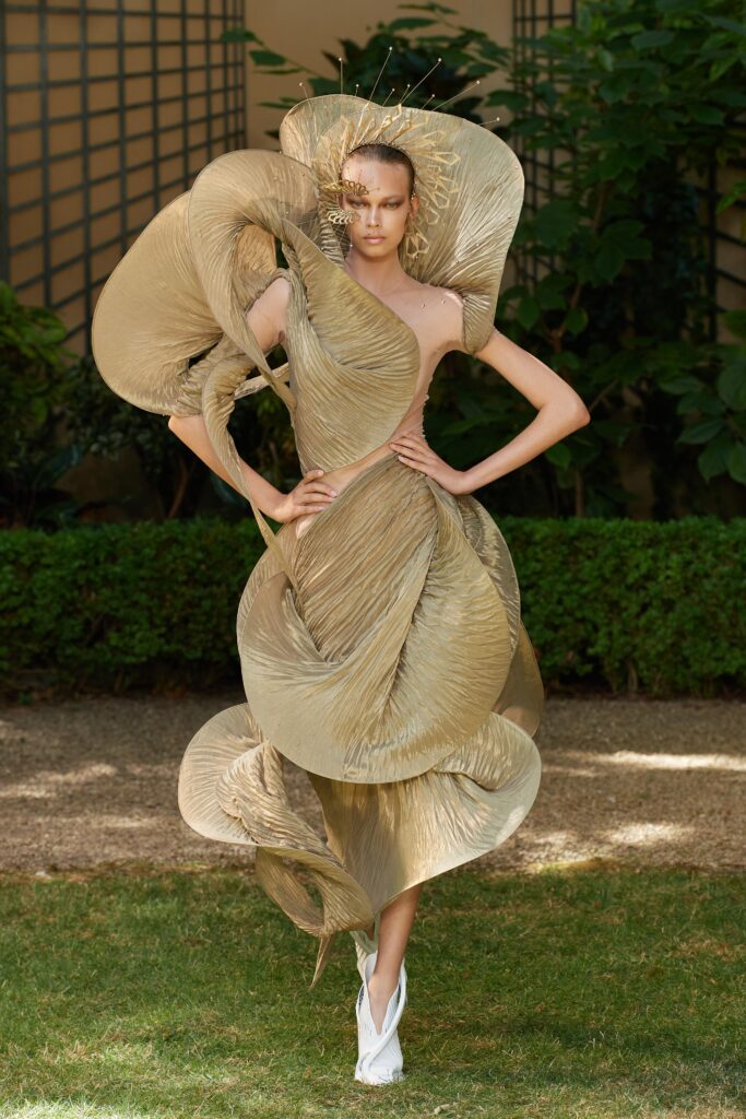 A fitted gold silk dress with a sleeveless design and asymmetric silhouette.