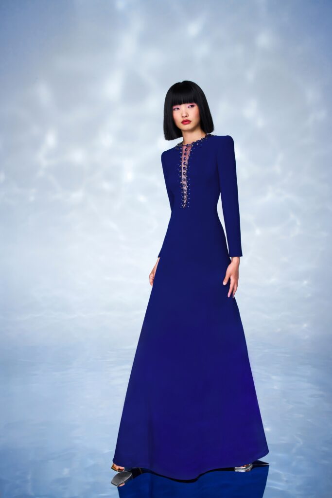 A fitted blue silk gown with long sleeves and a high neckline featuring button details.