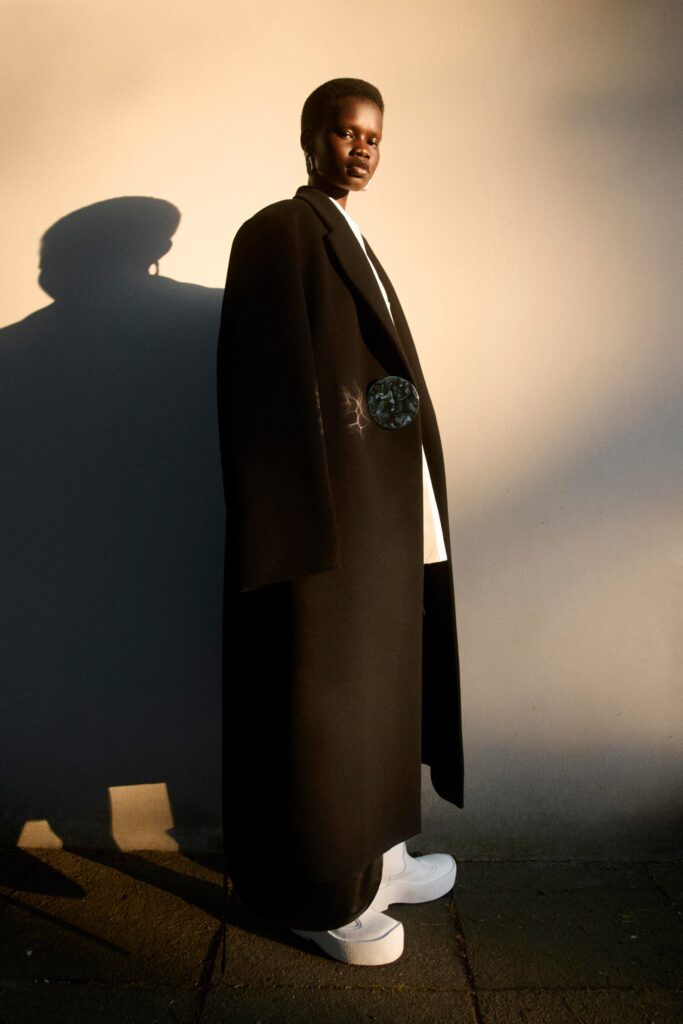 An oversized black wool coat with long sleeves and a layered design.