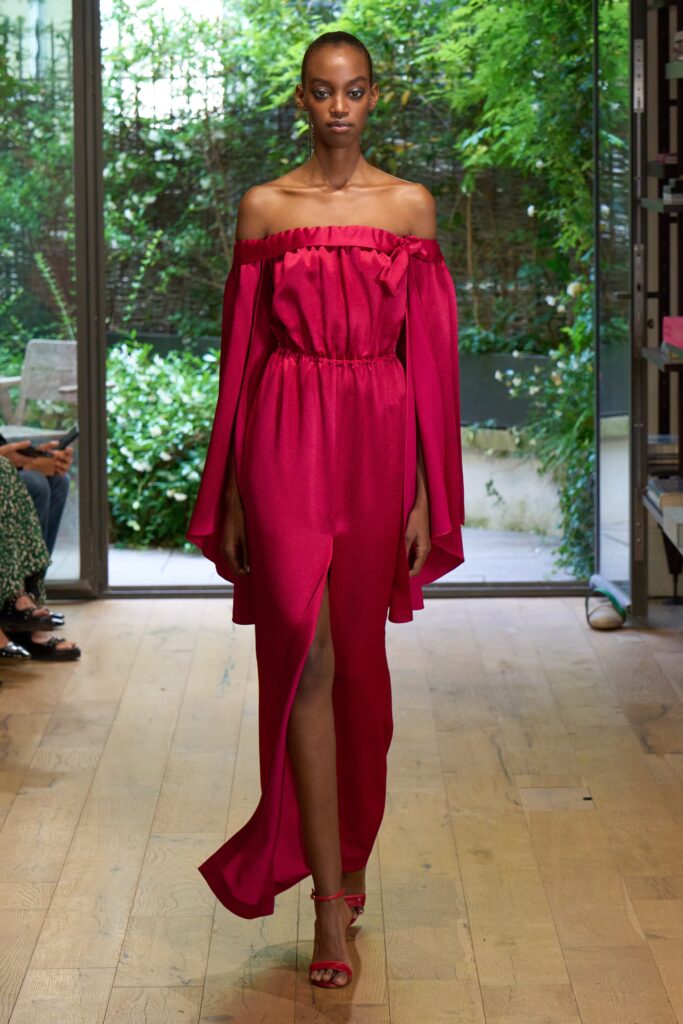 A fitted red silk off-shoulder dress with a maxi length and a side slit.