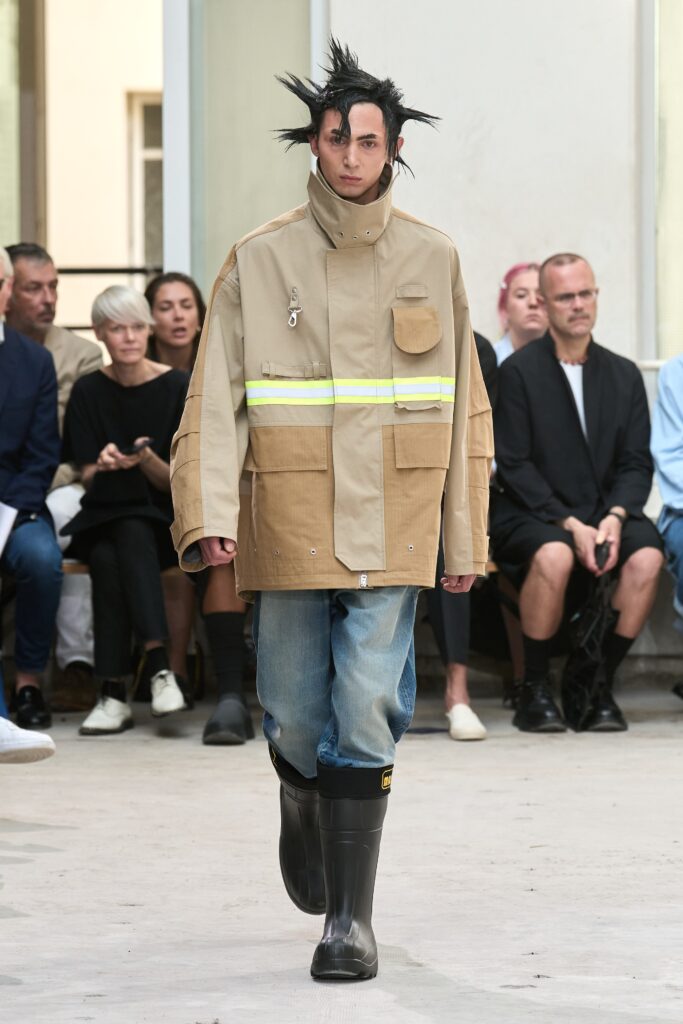 An oversized beige jacket with long sleeves and blue denim pants, featuring a layered design.