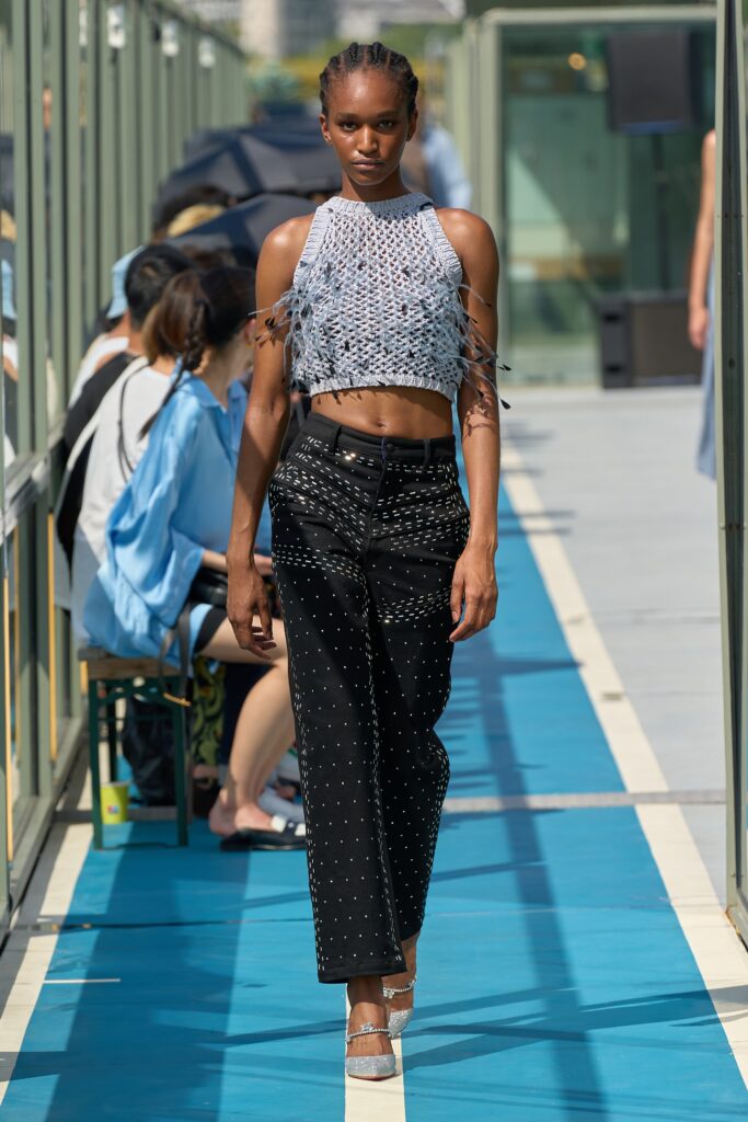 A fitted sleeveless top with embroidered details paired with high-waisted black pants.
